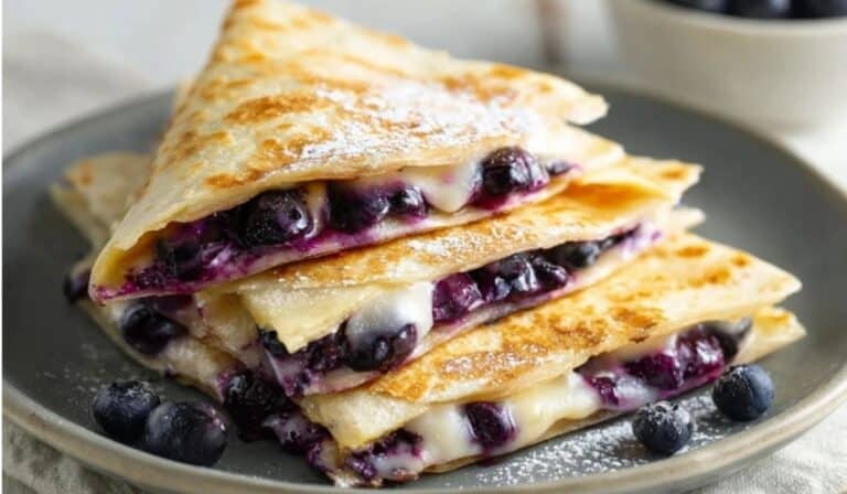 Blueberry Breakfast Quesadilla stacked on a gray plate with fresh berries