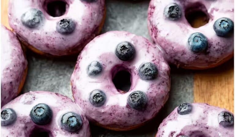 Blueberry Cake Donuts topped with fresh blueberries and glaze on parchment