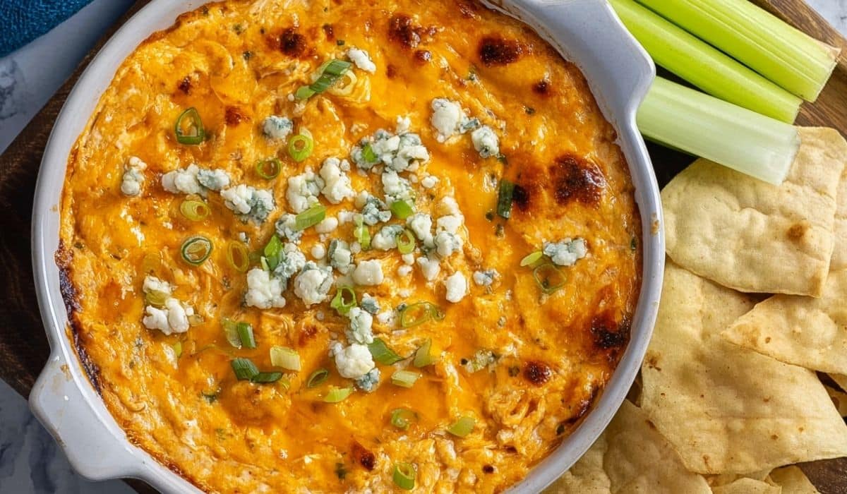 Healthy Buffalo Chicken Dip served with celery sticks and pita chips in a ceramic bowl