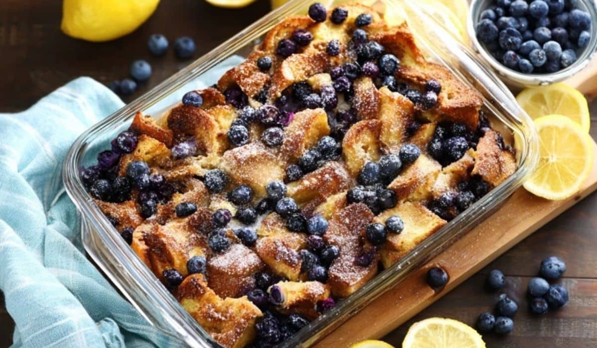 Overnight Lemon Blueberry French Toast in a glass dish with fresh blueberries and lemon