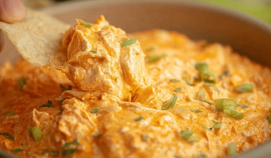 Buffalo Chicken Dip in a Crock Pot with tortilla chip scoop