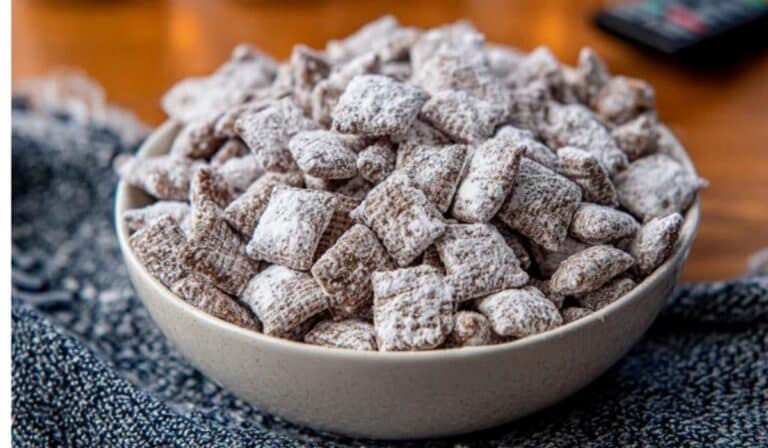 Delicious Homemade Puppy Chow in a white bowl on cozy winter table