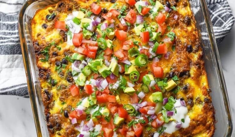 Mexican Breakfast Casserole topped with tomatoes, avocado, jalapeños, and sour cream