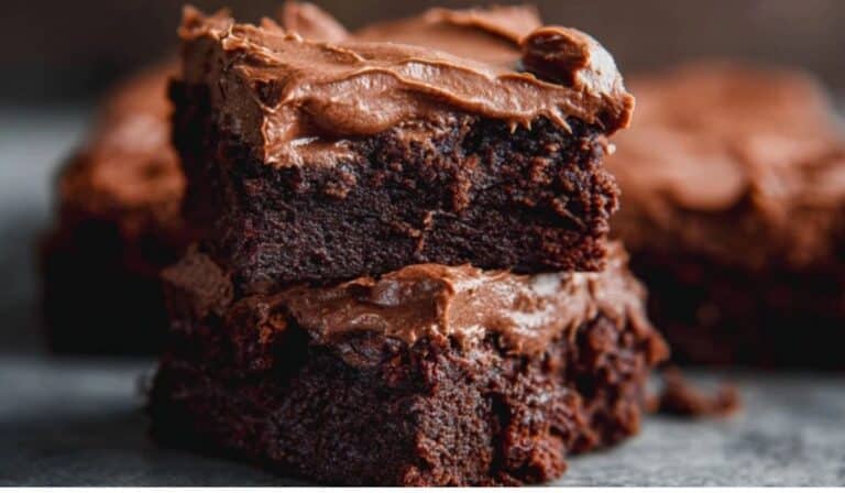 Chewy Fudgy Frosted Brownies stacked on plate with glossy frosting