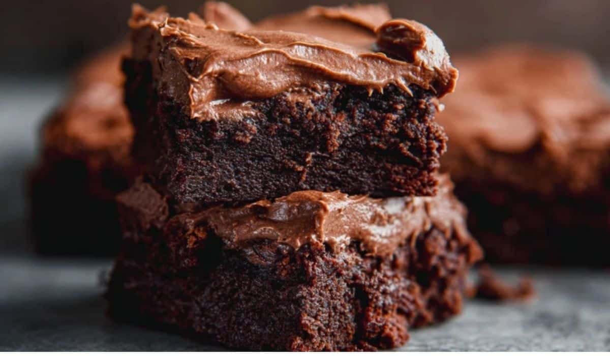 Chewy Fudgy Frosted Brownies stacked on plate with glossy frosting