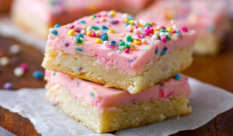 Frosted Sugar Cookie Bars on wooden table with sprinkles