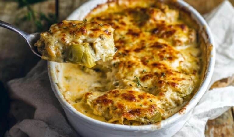 Artichoke and Chicken Bake in a white pan with golden bubbly cheese