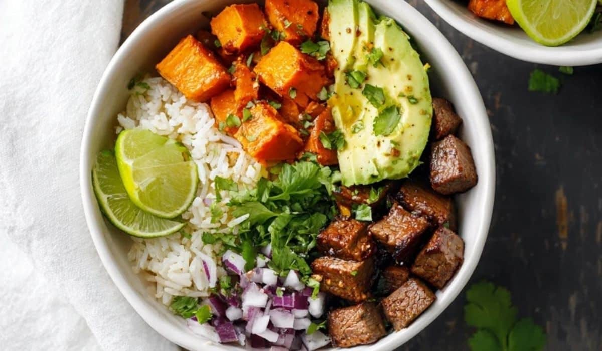Chipotle steak and sweet potato bowls with avocado and lime on a rustic table