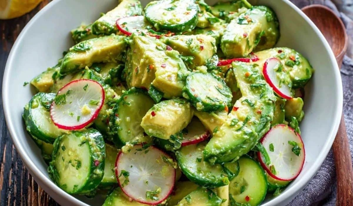 Cucumber avocado lemon salad in a white bowl with radish and herbs