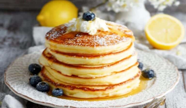 Stack of lemon ricotta pancakes with blueberries and syrup