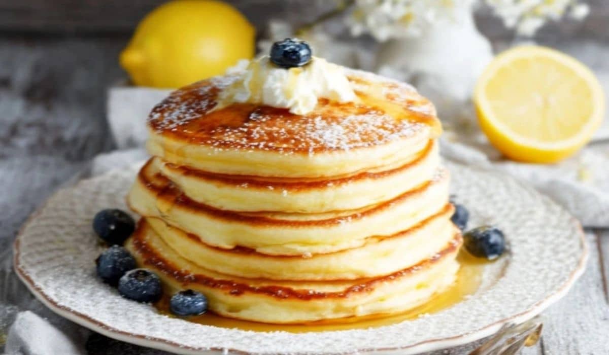 Stack of lemon ricotta pancakes with blueberries and syrup
