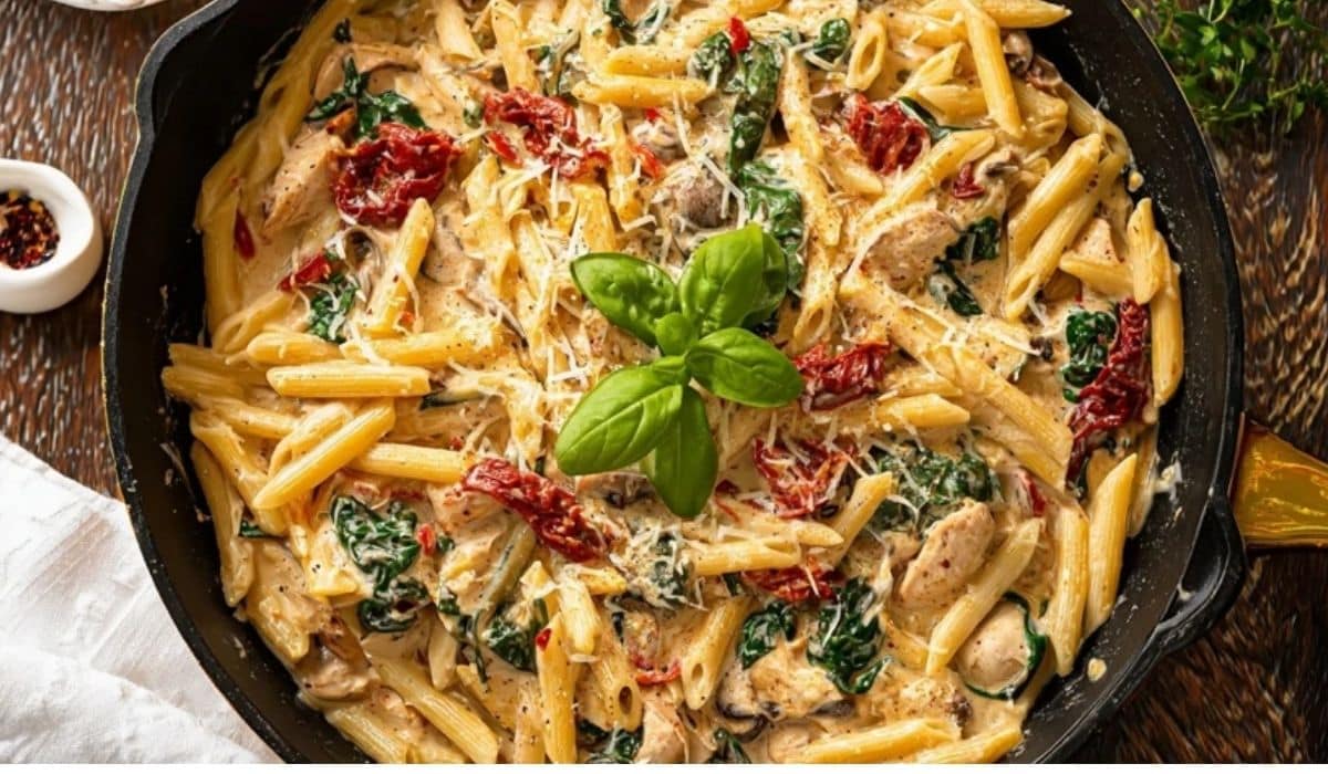 One-pot creamy Tuscan pasta in a cast-iron skillet with spinach and sun-dried tomatoes