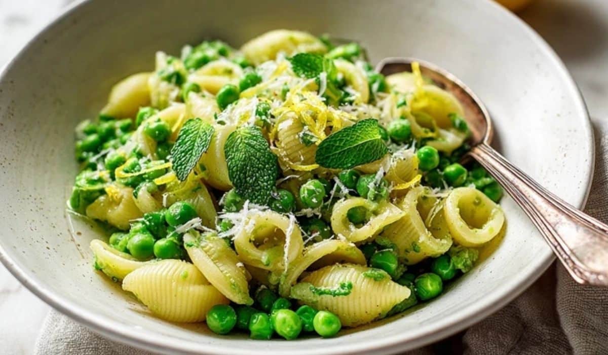 Pea and mint pasta side in a white bowl with lemon zest and Parmesan