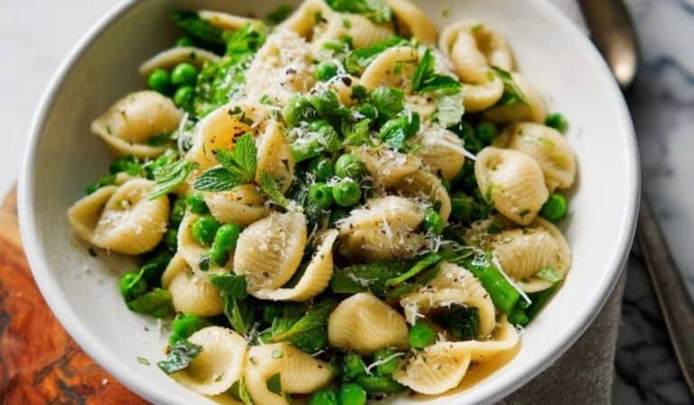 Spring pasta with peas in a white bowl with lemon zest and herbs