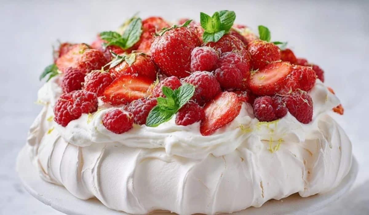 Strawberry pavlova spring cake with whipped cream and strawberries on a white stand